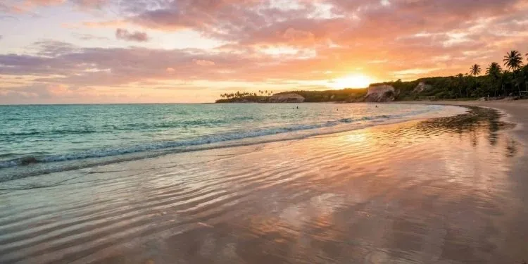 Praia de João Pessoa ao amanhecer, com o sol baixo e o mar calmo